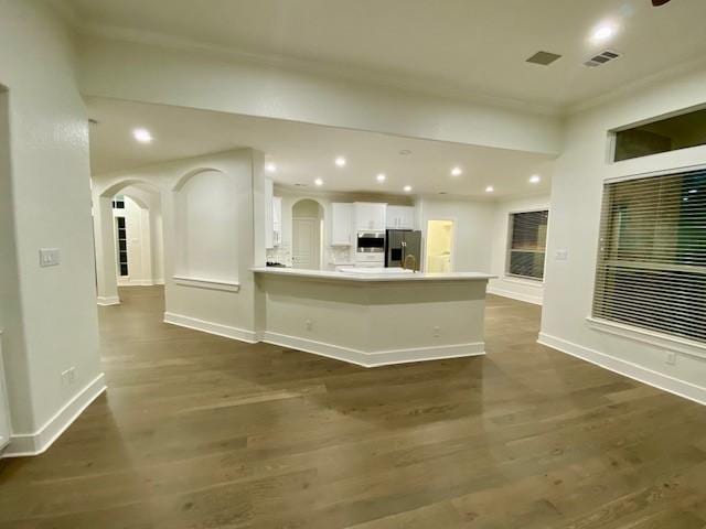 kitchen featuring white cabinetry, appliances with stainless steel finishes, dark hardwood / wood-style flooring, and kitchen peninsula