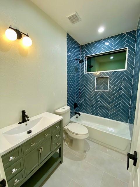 full bathroom with vanity, tiled shower / bath combo, tile patterned floors, and toilet