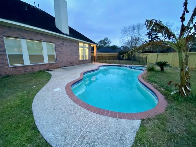 view of pool with a patio and a lawn