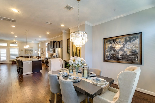 dining area with ornamental molding, dark wood-type flooring, and ceiling fan with notable chandelier