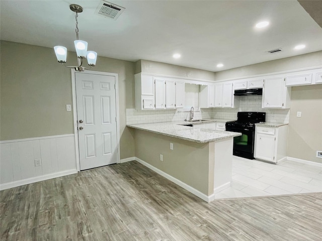 kitchen featuring black gas range oven, hanging light fixtures, white cabinets, kitchen peninsula, and light wood-type flooring