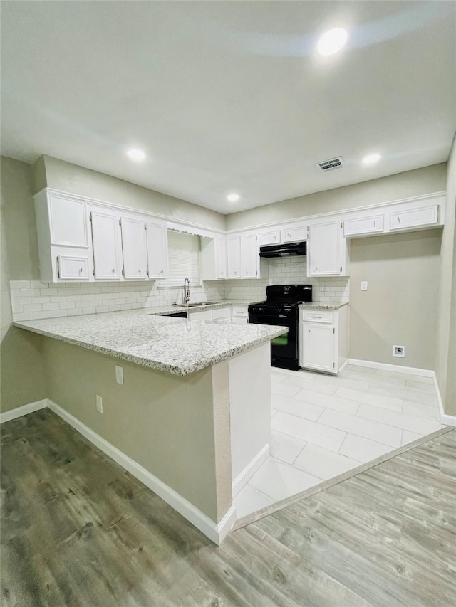 kitchen featuring sink, white cabinetry, black range oven, kitchen peninsula, and light stone countertops