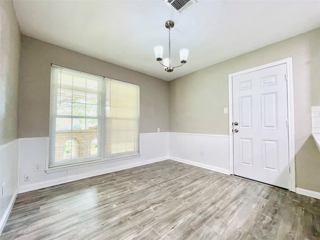 unfurnished dining area featuring an inviting chandelier and wood-type flooring