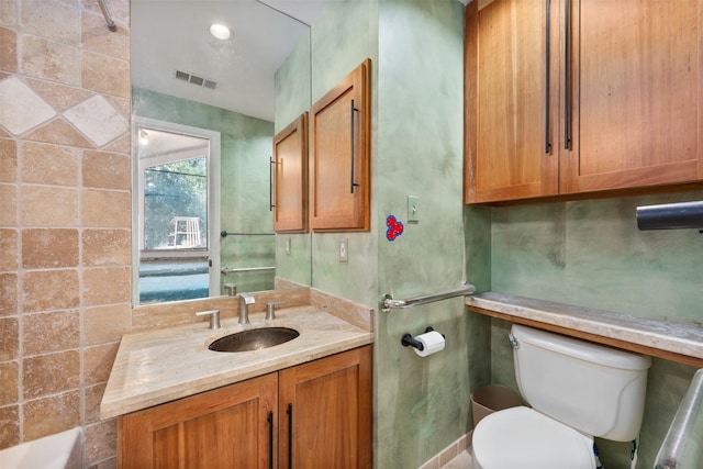 bathroom with vanity, toilet, and a tub