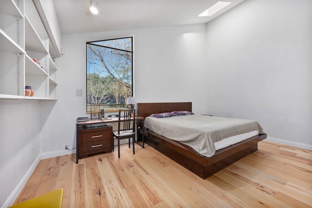 bedroom featuring light hardwood / wood-style floors and vaulted ceiling with skylight