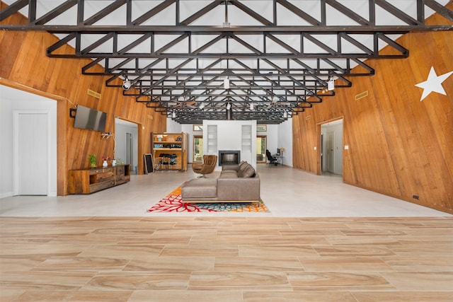 living room featuring beam ceiling, high vaulted ceiling, and wood walls