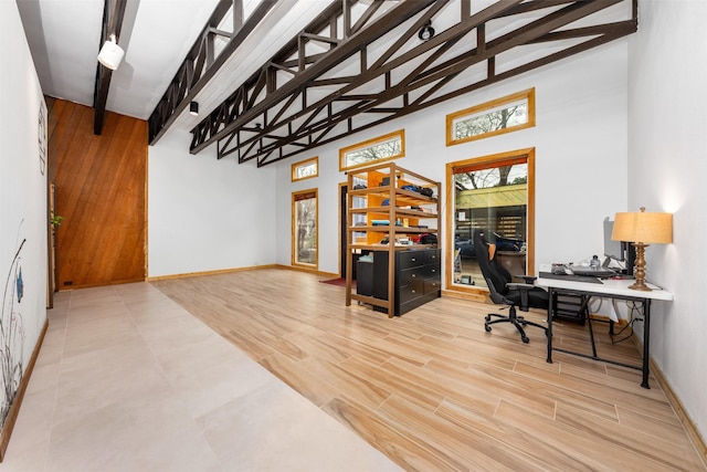 office with beamed ceiling, high vaulted ceiling, and light hardwood / wood-style flooring