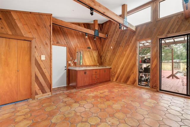 interior space with beamed ceiling, high vaulted ceiling, track lighting, and wooden walls