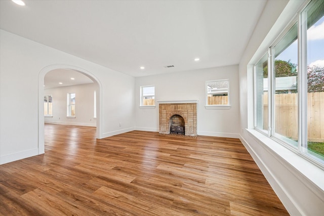 unfurnished living room featuring a brick fireplace and light wood-type flooring