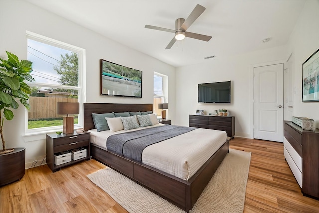 bedroom with multiple windows, light hardwood / wood-style floors, and ceiling fan