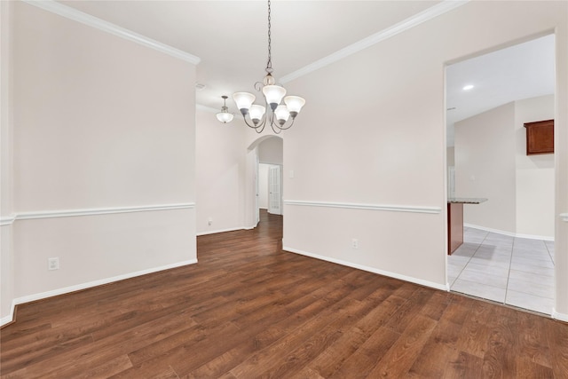 empty room with dark hardwood / wood-style flooring, a notable chandelier, and ornamental molding