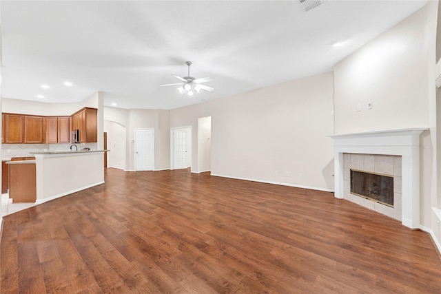 unfurnished living room featuring dark wood-type flooring, a fireplace, and ceiling fan