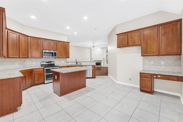 kitchen with sink, light stone counters, light tile patterned floors, a kitchen island, and stainless steel appliances