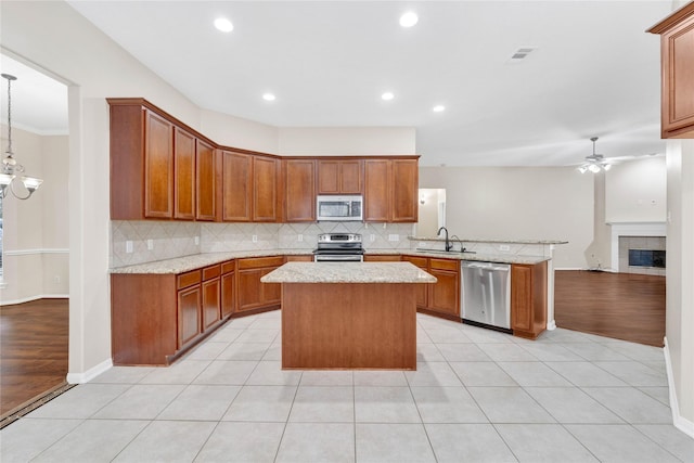 kitchen with sink, ceiling fan, stainless steel appliances, a center island, and light tile patterned flooring