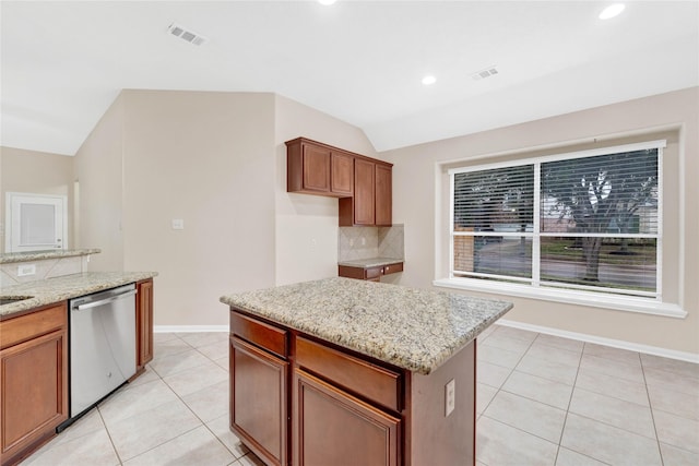 kitchen with light stone counters, stainless steel dishwasher, decorative backsplash, and a kitchen island