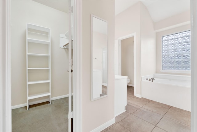 bathroom with tile patterned flooring, a bathing tub, and toilet