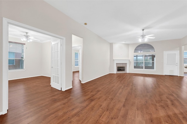 unfurnished living room featuring dark hardwood / wood-style flooring, a tile fireplace, and ceiling fan