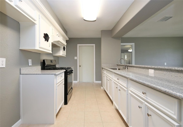 kitchen with white cabinets, sink, stainless steel gas range, and light stone counters