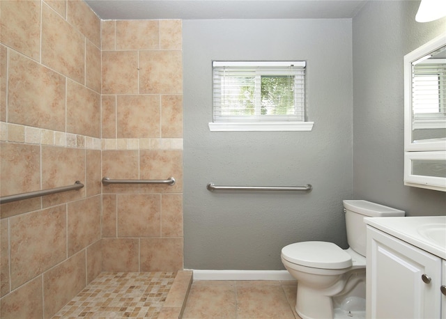 bathroom with tile patterned flooring, vanity, a tile shower, and toilet