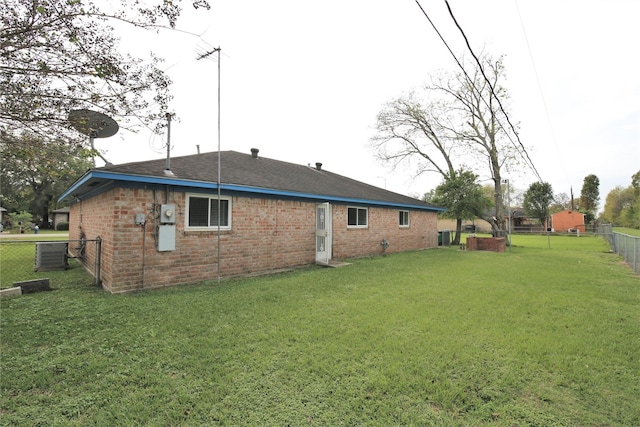 back of property with central AC and a lawn