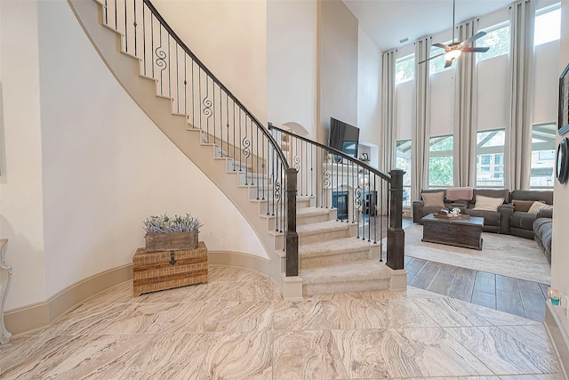 staircase featuring ceiling fan and a towering ceiling