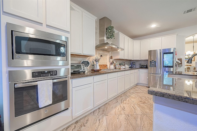 kitchen featuring stainless steel appliances, tasteful backsplash, wall chimney range hood, and white cabinets