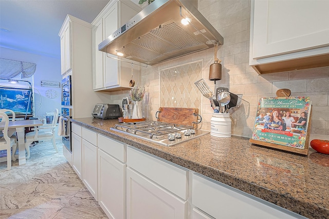 kitchen featuring wall chimney exhaust hood, stainless steel appliances, decorative backsplash, and white cabinets