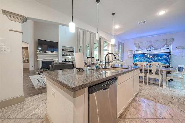 kitchen featuring sink, dark stone countertops, stainless steel dishwasher, a kitchen island with sink, and white cabinets