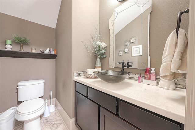 bathroom featuring vaulted ceiling, vanity, a textured ceiling, and toilet