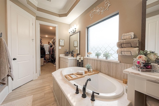 bathroom featuring vanity, ornamental molding, and tiled bath