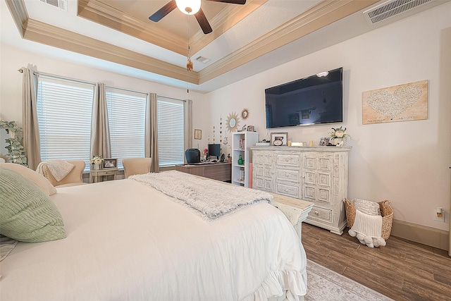 bedroom with ceiling fan, ornamental molding, a tray ceiling, and hardwood / wood-style floors