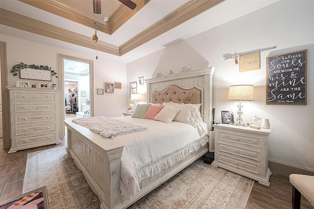 bedroom featuring ceiling fan, a towering ceiling, ornamental molding, dark hardwood / wood-style flooring, and a raised ceiling