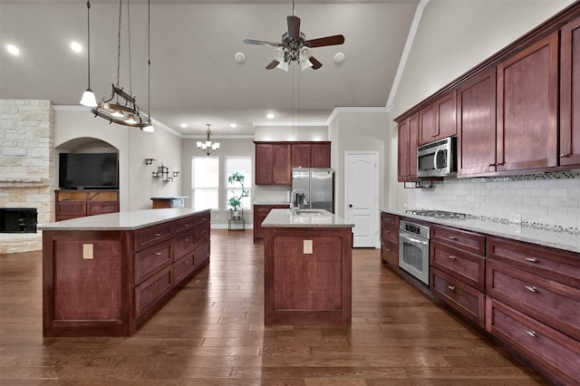 kitchen with appliances with stainless steel finishes, a center island with sink, decorative backsplash, and decorative light fixtures