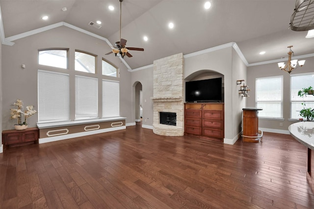 unfurnished living room with a healthy amount of sunlight, ceiling fan with notable chandelier, a fireplace, and dark wood-type flooring