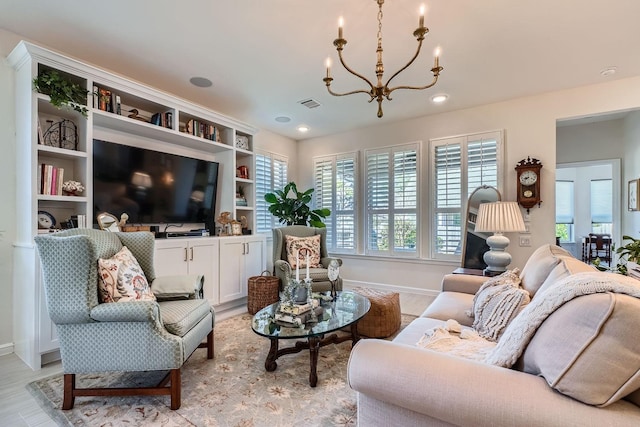 living area with an inviting chandelier, baseboards, visible vents, and light wood finished floors