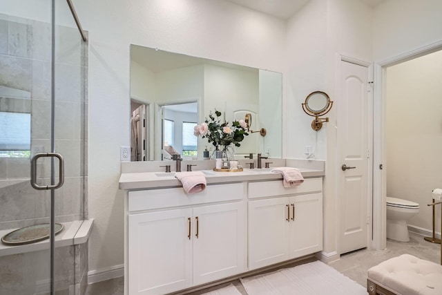 full bathroom featuring toilet, a sink, baseboards, double vanity, and a stall shower