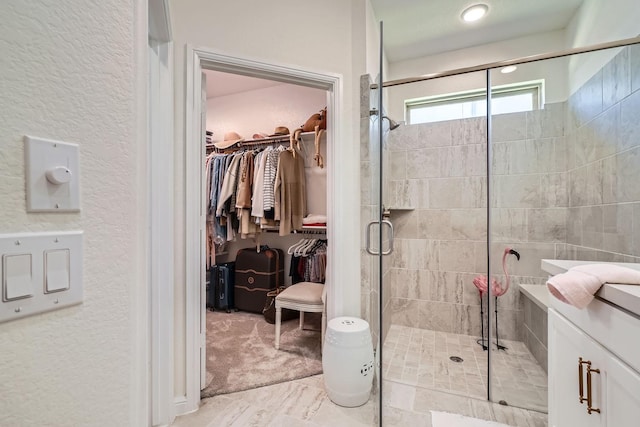 bathroom featuring a stall shower, a walk in closet, and a textured wall