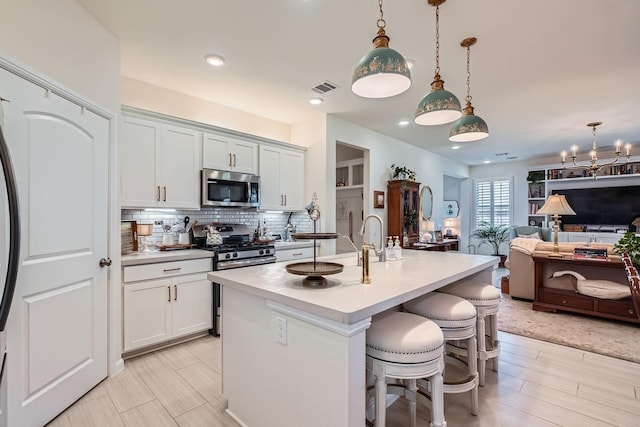 kitchen with visible vents, decorative backsplash, open floor plan, light countertops, and stainless steel appliances