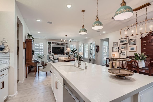 kitchen featuring dishwasher, plenty of natural light, a sink, and a notable chandelier