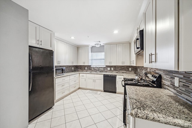 kitchen featuring sink, white cabinetry, light stone countertops, decorative backsplash, and black appliances