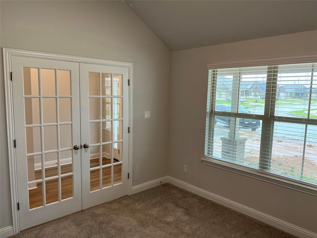 empty room with lofted ceiling, french doors, and carpet flooring