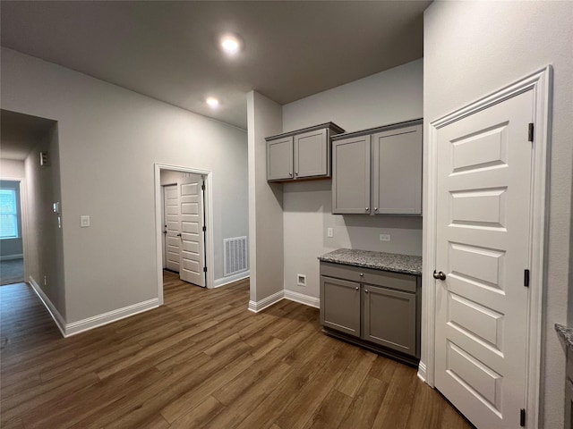 kitchen featuring dark hardwood / wood-style flooring, light stone countertops, and gray cabinetry