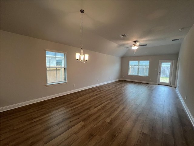 spare room featuring lofted ceiling, a healthy amount of sunlight, ceiling fan with notable chandelier, and dark hardwood / wood-style flooring