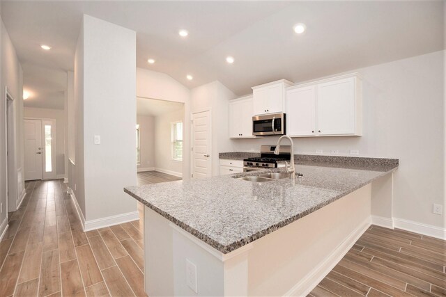 kitchen featuring light stone counters, stainless steel appliances, white cabinetry, a sink, and a peninsula