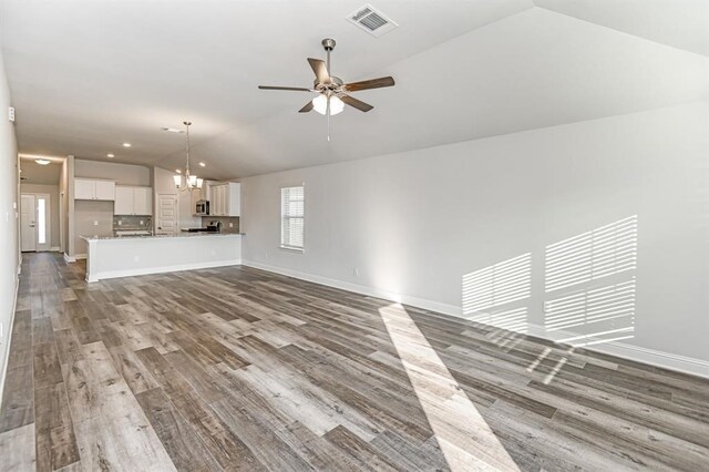 unfurnished living room featuring lofted ceiling, visible vents, a ceiling fan, wood finished floors, and baseboards