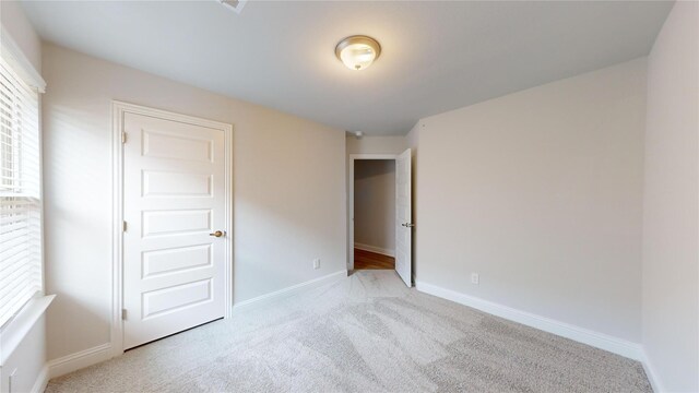 unfurnished bedroom with light colored carpet and baseboards