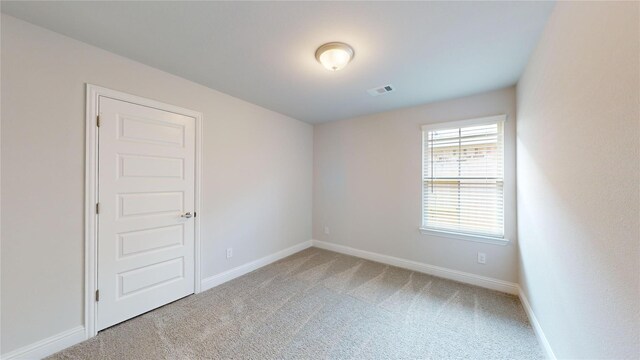 carpeted empty room featuring visible vents and baseboards