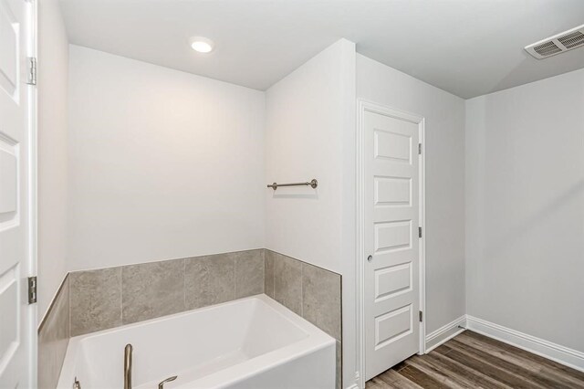 full bath with a garden tub, baseboards, visible vents, and wood finished floors