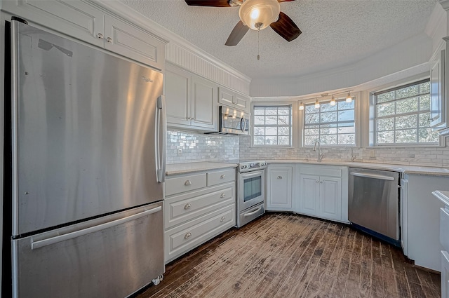 kitchen with appliances with stainless steel finishes, white cabinetry, sink, backsplash, and a textured ceiling