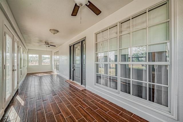 unfurnished sunroom with ceiling fan